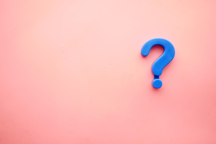 A question mark on a pink background symbolizing asking questions before applying for a personal loan.